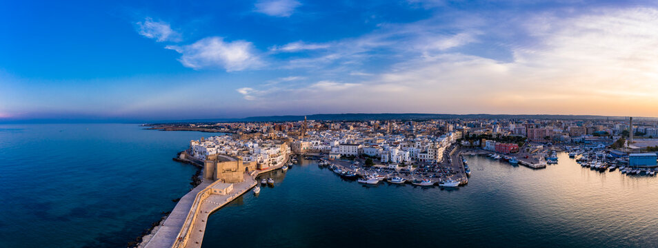Italy, Apulia, Monopoli, Aerial view of sea and old town at sunset
