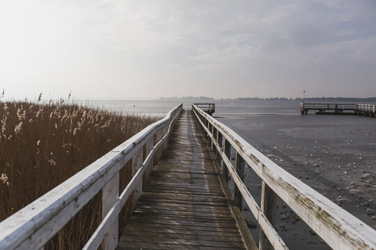 Germany, Mecklenburg-Western Pomerania, Wieck, wooden boardwalk in winter, frozen bodden