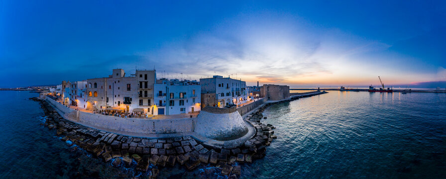 Italy, Apulia, Monopoli, Aerial view of sea and old town at sunset