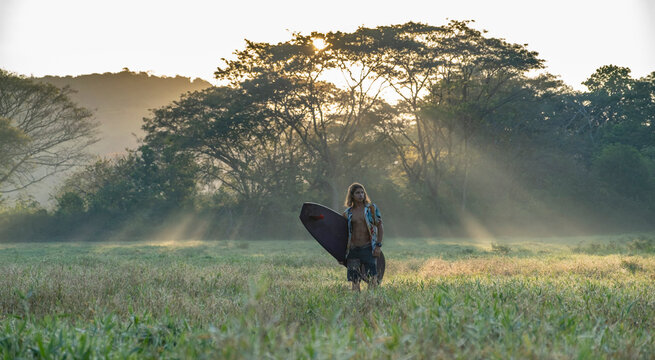 Young surfer on the way to the beach at sunrise, Costa Rica