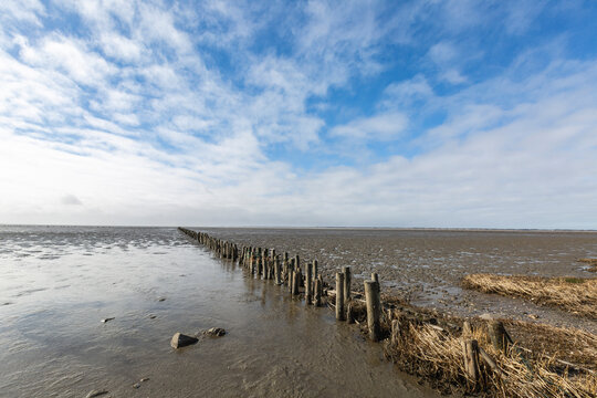 Denmark, Romo, Clouds over old groyne stretching along mud flat