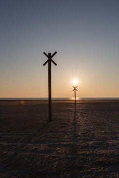 Denmark, Romo, Silhouettes of distance markers on coastal beach at sunset