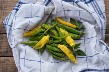 Yellow and green chilies (capsicum), hot peppers, with leaves on table