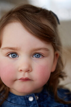 Portrait of toddler girl with blue eyes and red cheeks