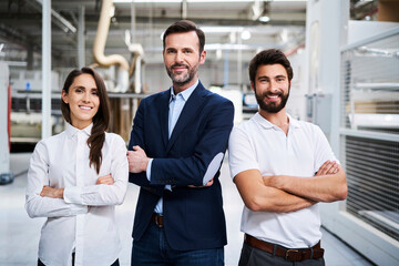 Portrait of confident businessman and employees in a factory