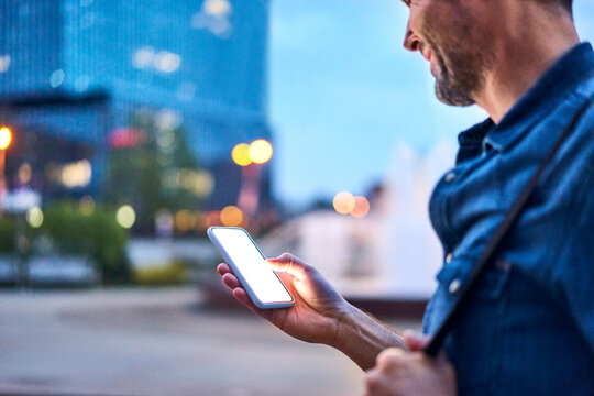 Close up of man using smartphone while out in the city during evening - Powered by Adobe