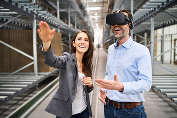 Happy businesswoman and businessman wearing VR glasses in factory