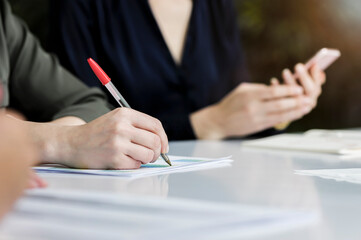 Close-up of businesswoman taking notes during a meeting in office