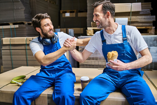 Two happy workers having lunch break in factory