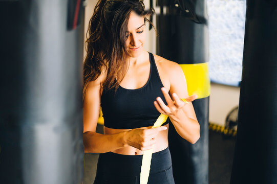 Female boxer bandaging her hands in a gym