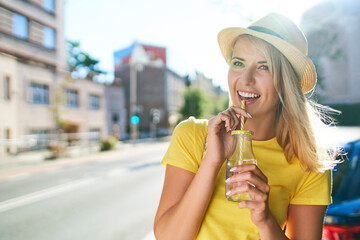 Happy young woman enjoying a drink in the city