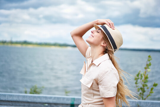 Smiling woman with closed eyes leaning back at the lakeside