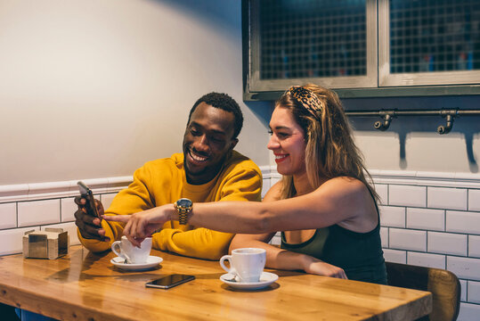 Portrait of smiling couple in a coffee shop using smartphone