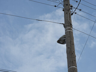An old wooden electric pole with a lamp and electricity cables hanging on it