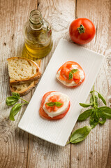 Caprese salad traditional italian recipe with mozzarella tomato basil and bread over white dish