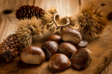 raw chestnuts with hedgehog over wooden table