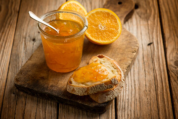 orange marmalade with bread over wooden background