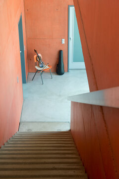 Violin, bow, sheet music on wooden chair and violin case leaning at wall