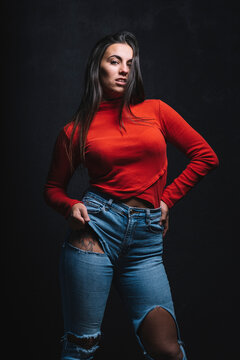 Portrait of young woman with tattoo on tigh posing in front of black background