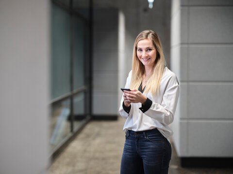 Smiling businesswoman using cell phone in modern office