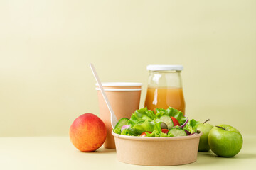 Healthy vegetable salad in recyclable cardboard container. Food delivery, healthy food menu for home or office concept. Green background, side view