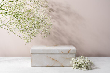 Cosmetic presentation podium made of paper marble gift box . Product display with white flowers in...