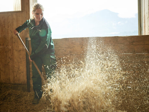 Female farmer working with straw on a farm
