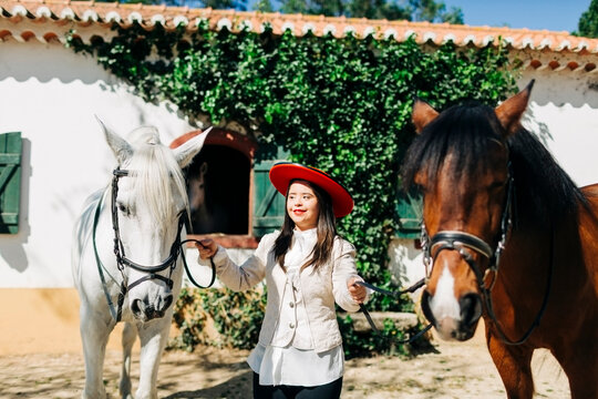 Teenager with down syndrome wearing red hat with two horses