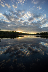 An epic lake view in Sweden near Glommersträsk. with open and cloudy sky and reflecting lake surface and a setting sun.