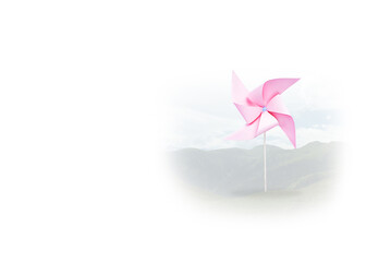 Pink paper windmill on defocused landscape background. Sustainable energy concept