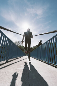 Rear view of disabled athlete with leg prosthesis running on a bridge