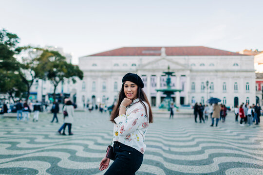 Young female traveller wearing a beret and posing at Rossio square, Lisbon, Portugal