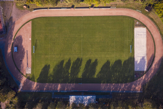 Germany, Baden-Wurttemberg, Freiburg im Breisgau, Aerial view of running track surrounding empty football field