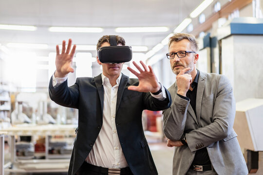 Two businessmen with VR glasses in factory
