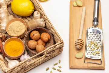Walnuts, garlic, ginger root and spices in wicker basket. Grater and chopped ginger root.