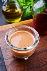 Classic traditional mustard raspberry dressing with mayonnaise, vinegar and olive oil served as close-up in a glass bowl on a wooden board