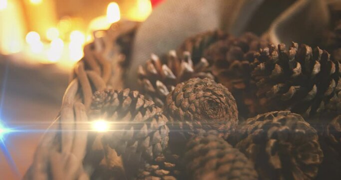 Composition of light over christmas decorations with pine cones and candles