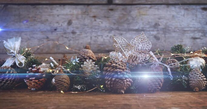 Composition of light over christmas decorations with pine cones