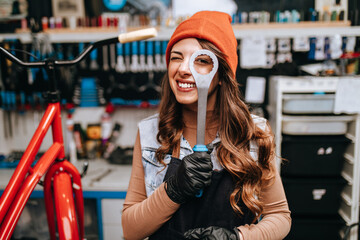 Beautiful young female mechanic having fun and enjoying while repairing bicycles in a workshop..