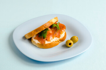 Sandwich with red fish and cream cheese on white toast. Fish sandwich. Salmon sandwich. Sandwiches with red fish on a blue plate. Photo of food.