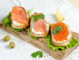Sandwich with red fish and caviar on white toast. Fish sandwich. Salmon sandwich. Sandwiches with red fish on a blue plate. Traditional appetizer. Photo of food.