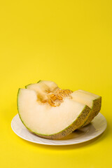 three slices of melon on a plate on a yellow background, copy space