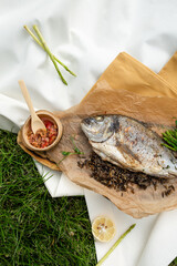 Grilled Dorado fish on a wooden board with paper with lemon, salad, sauce. top view