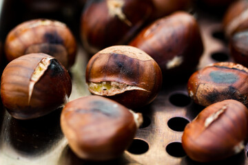 Group of beautifully roasted chestnuts on metal plate