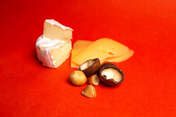 Camembert cheese and macadamia nuts on a red background