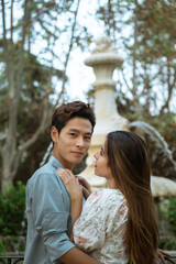 Fototapeta premium ATTRACTIVE KOREAN YOUNG MAN HUGGING EUROPEAN GIRL AT THE PARK IN AUTUMN