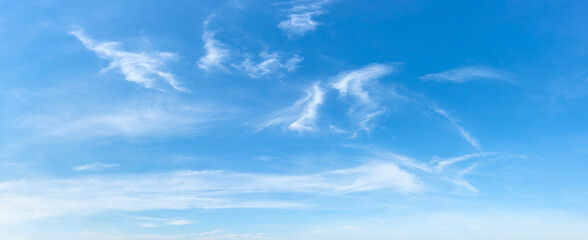 Clear azure sky with few wispy cirrus clouds. Sparse translucent white clouds in the blue sky on a sunny day. Concepts of weather forecast, vacations, travel and season. Sky only wide panorama.  - obrazy, fototapety, plakaty