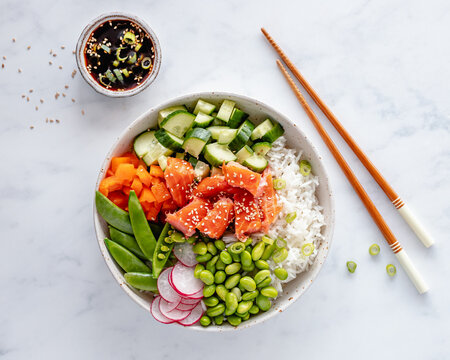 Salmon poke bowl with rice, edamame beans, cucumber, radish, mange tout, spring onion, bell peppers and a soy dipping sauce