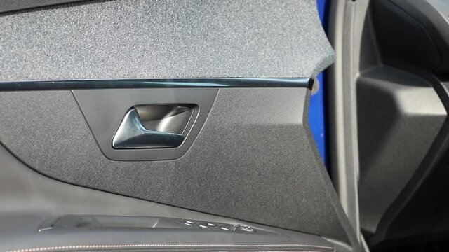 Chrome-plated handle for opening the driver's door from the inside. Door card of a modern car. Close-up.