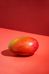 fresh mango, table background in sunlight, modern stilllife, red background, harsh light